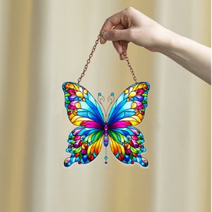 May include: A colorful stained glass butterfly suncatcher with a copper chain for hanging. The butterfly has blue, yellow, red, green, and purple wings.