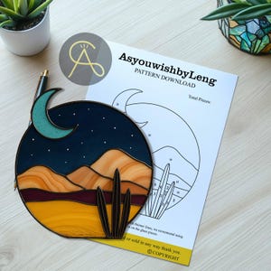 Pode incluir: Uma obra de arte em vitral circular que retrata uma paisagem des&eacute;rtica sob um c&eacute;u noturno. O design inclui uma lua crescente, estrelas e cactos. Uma folha de download de padr&atilde;o &eacute; vis&iacute;vel, com o texto "AsyouwishbyLeng" e "PATTERN DOWNLOAD".
