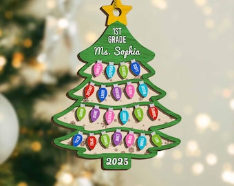 May include: A wooden Christmas tree ornament with a green tree shape, a gold star, and the text "1st Grade Ms. Sophia." The ornament features colorful light bulb shapes with student names and the year 2025.