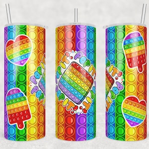 May include: Three rainbow-colored stainless steel tumblers with a pop it design. The tumblers feature a heart, a popsicle, and a square pop it design. The text "Pop It! Pop It! Pop It!" is printed on the tumblers.