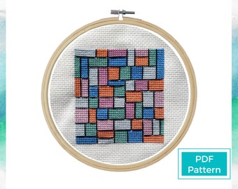 May include: A cross-stitch pattern in a wooden embroidery hoop. The design features a geometric pattern of rectangular blocks in various colors, including blue, orange, pink, and green. The text "PDF Pattern" is in a white box in the lower right corner.