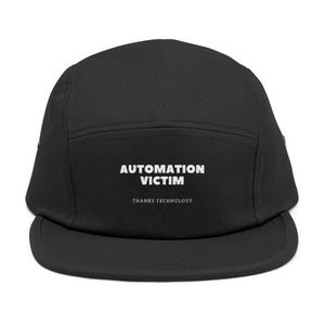 Peut inclure: Casquette noire à cinq panneaux avec une visière plate. Le texte blanc "AUTOMATION VICTIM" est imprimé au-dessus de "THANKS TECHNOLOGY". Un accessoire décontracté.