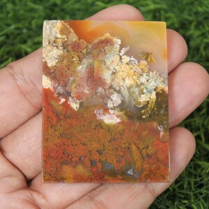 K&ouml;nnte beinhalten: Ein rechteckiges St&uuml;ck Achat mit einer Vielzahl von Farben, darunter Orange, Rot, Gelb und Braun. Der Achat hat ein wirbelndes Muster und eine glatte, polierte Oberfl&auml;che.