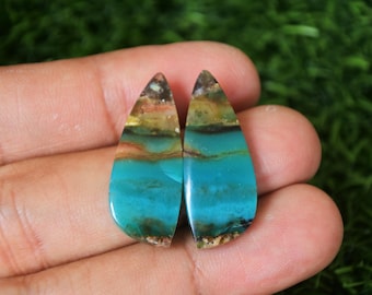 Op de afbeelding: Paar traanvormige cabochons met een blauw, groen en bruin opaalpatroon.