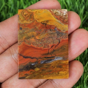 May include: A polished slab of red, yellow, and brown agate with a swirling pattern. The agate is a natural stone with a smooth, polished surface.