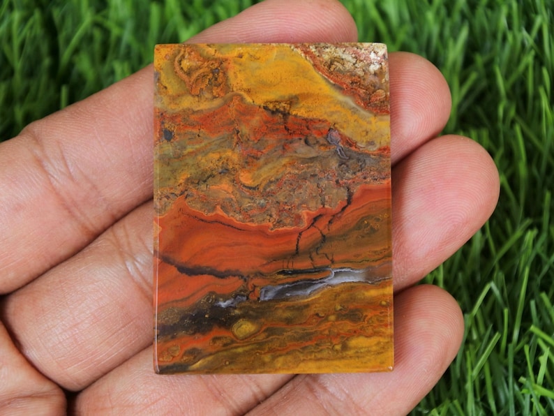 Peut inclure: Une dalle d'agate polie de couleur rouge, jaune et marron avec un motif tourbillonnant. L'agate est une pierre naturelle avec une surface lisse et polie.