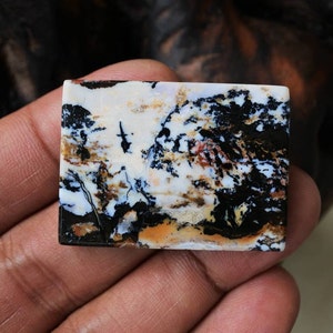 Puede incluir: Un cabuj&oacute;n rectangular de &aacute;gata de color blanco, negro y marr&oacute;n con un patr&oacute;n de remolino. El cabuj&oacute;n mide aproximadamente 5 cm de largo y 2,5 cm de ancho.