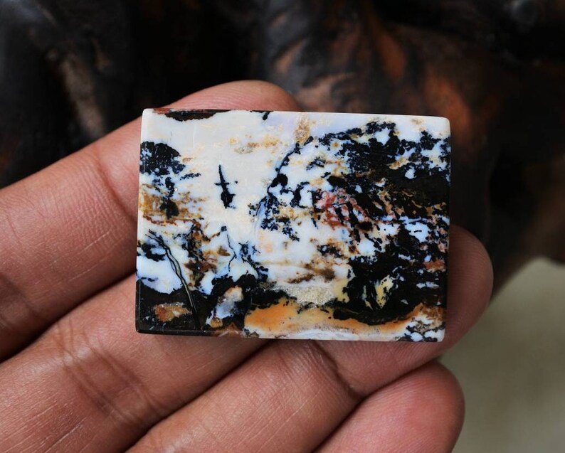 Puede incluir: Un cabuj&oacute;n rectangular de &aacute;gata de color blanco, negro y marr&oacute;n con un patr&oacute;n de remolino. El cabuj&oacute;n mide aproximadamente 5 cm de largo y 2,5 cm de ancho.