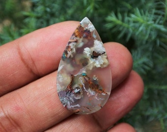 May include: A teardrop-shaped cabochon of agate with a white, brown, and rust-colored pattern. The agate has a translucent appearance and is set in a silver bezel.