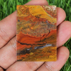 Peut inclure: Une dalle rectangulaire d'agate polie avec un motif color&eacute; de rouge, orange, jaune, brun et noir. L'agate a un aspect naturel et organique.