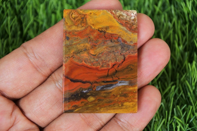 Peut inclure: Une dalle rectangulaire d'agate polie avec un motif color&eacute; de rouge, orange, jaune, brun et noir. L'agate a un aspect naturel et organique.