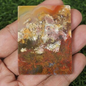 K&ouml;nnte beinhalten: Nahaufnahme einer bunten Achatplatte mit Schattierungen von Rot, Orange, Gelb, Wei&szlig; und Braun. Der Achat hat ein nat&uuml;rliches, organisches Muster.