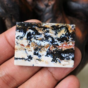 Puede incluir: Un cabuj&oacute;n rectangular de &aacute;gata pulido, negro, blanco y marr&oacute;n con un patr&oacute;n de remolino.