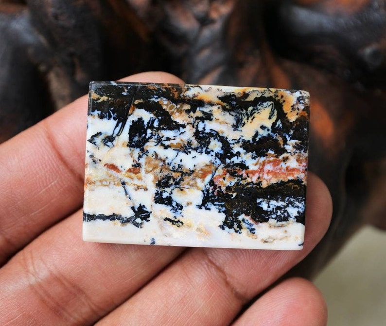 Puede incluir: Un cabuj&oacute;n rectangular de &aacute;gata pulido, negro, blanco y marr&oacute;n con un patr&oacute;n de remolino.