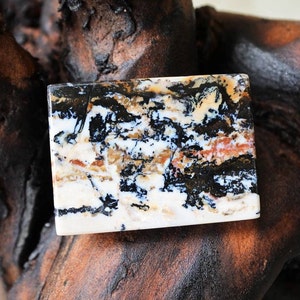 Puede incluir: Una losa rectangular de &aacute;gata pulida con un patr&oacute;n de remolino blanco, negro y marr&oacute;n. La &aacute;gata tiene una superficie lisa y pulida.