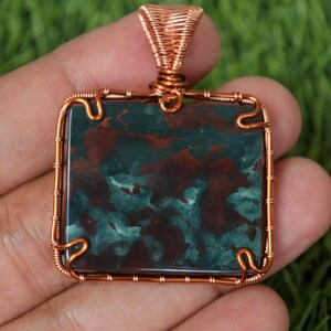 May include: A copper wire wrapped pendant featuring a square green and red jasper stone.