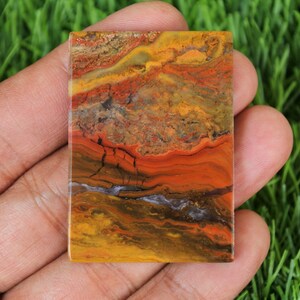 Peut inclure: Une dalle rectangulaire d'agate polie avec un motif color&eacute; de rouge, orange, jaune, brun et noir. L'agate a un aspect stratifi&eacute; et ruban.