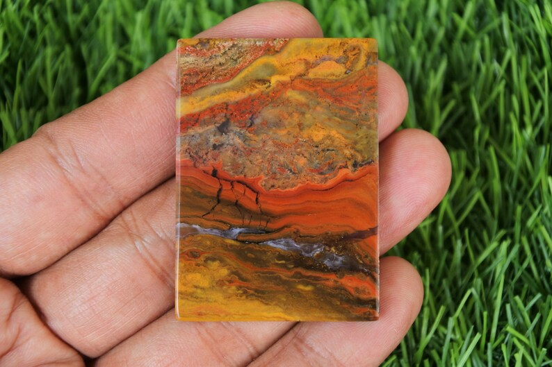 Peut inclure: Une dalle rectangulaire d'agate polie avec un motif color&eacute; de rouge, orange, jaune, brun et noir. L'agate a un aspect stratifi&eacute; et ruban.