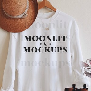 May include: White sweatshirt with the text "MOONLIT MOCKUPS" printed on the front. A brown hat and brown boots are also in the image.
