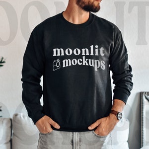 Könnte beinhalten: Ein schwarzer Pullover mit dem Text "moonlit mockups" und einem Kamerasymbol auf der Vorderseite.