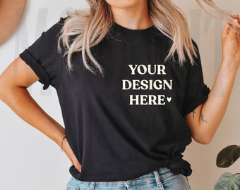 May include: A black t-shirt with the text "YOUR DESIGN HERE" in white lettering. The shirt is being worn by a person with long blonde hair and blue jeans.