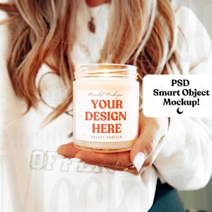 May include: A white candle with a label that says "Your Design Here" and "Velvet Vanilla". The candle is lit and being held by a person. The text "PSD Smart Object Mockup!" is in a speech bubble.