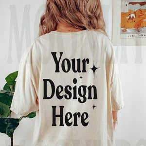 May include: An oversized cream coloured t-shirt with the text "Your Design Here" in black with small stars on either side of the text.