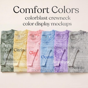 May include: Six Comfort Colors crewneck t-shirts in a row, each in a different colour: Fern, Citrine, Clay, Ocean, Amethyst, and Smoke. The image displays the colorblast effect. The text "Comfort Colors" and "color display mockups" are at the top.