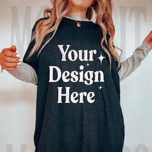 May include: A black oversized t-shirt with a white graphic that says "Your Design Here" and two small white stars. The shirt has long sleeves with a gray stripe on the sleeves.