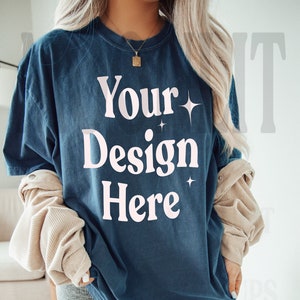 May include: A woman wearing a dark blue oversized t-shirt with the text "Your Design Here" in white. The shirt has a distressed look and is perfect for customizing with your own design.
