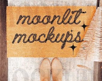 May include: A brown doormat with the text "moonlit mockups" in black rope lettering. The doormat is on a white rug with a pair of brown ankle boots on top of the rug.