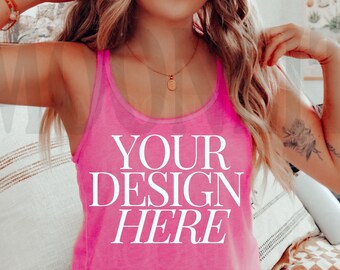 May include: A pink tank top with the text "YOUR DESIGN HERE" printed on the front. The tank top is being worn by a person sitting on a bed.