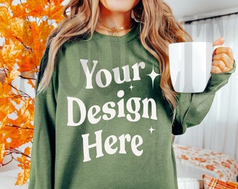 May include: A woman wearing a green sweatshirt with the text "Your Design Here" in white. She is holding a white mug in her right hand.