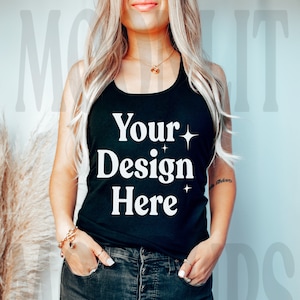 Puede incluir: Un top negro de tirantes con el texto "Your Design Here" en letras blancas. El top lo lleva puesto una persona con el pelo largo y rubio.