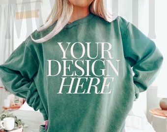 May include: A green sweatshirt with the text "YOUR DESIGN HERE" printed on the front. The sweatshirt is made of a soft, comfortable material and has a relaxed fit.