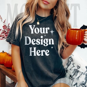 May include: A black t-shirt with the text "Your Design Here" in white. The shirt is being worn by a person with long blonde hair. The person is holding a mug in their right hand.