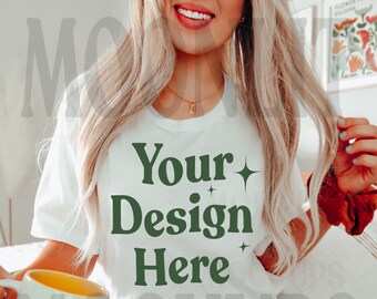 May include: A white t-shirt with the text "Your Design Here" in green letters with small stars on either side of the text. The shirt is being worn by a person with long blonde hair.
