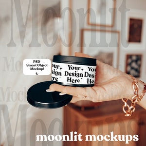 May include: A black metal tin with a white label that says "Your Design Here". The tin is being held by a hand with a gold chain bracelet.