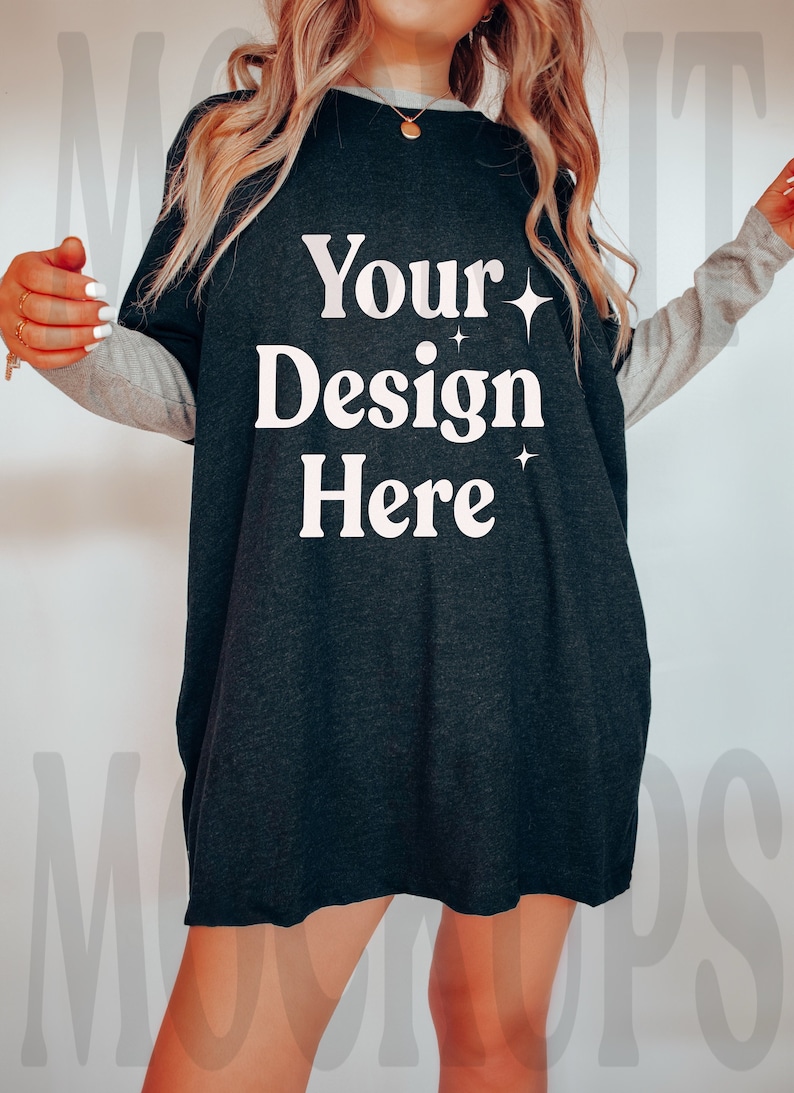 May include: A black oversized t-shirt with a white graphic that says "Your Design Here" and two small white stars. The shirt has long sleeves with a gray stripe on the sleeves.