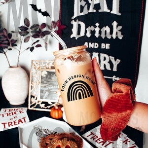 May include: A glass tumbler with a black and white rainbow design and the text "YOUR DESIGN HERE". The tumbler is filled with a brown beverage and has a wooden lid. The tumbler is being held by a hand wearing a red scrunchie.