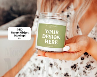 Peut inclure: Une bougie blanche dans un pot en verre transparent avec une étiquette verte qui dit "Moonlit Mockups Candle Co. Your Design Here Fragrance No. 2".