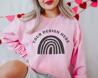 May include: A pink sweatshirt with a black rainbow graphic and the text "YOUR DESIGN HERE" printed on the front.