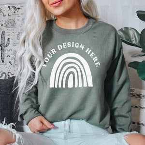 May include: A green sweatshirt with a white rainbow design and the text "YOUR DESIGN HERE" printed on the front.