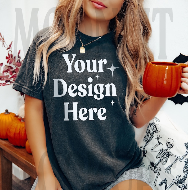 May include: A black t-shirt with the text "Your Design Here" in white. The shirt is being worn by a person with long blonde hair. The person is holding a mug in their right hand.