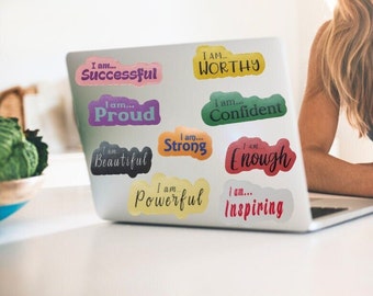 Puede incluir: Un ordenador portátil con pegatinas de colores que dicen "Yo soy... Exitoso", "Yo soy... Orgulloso", "Yo soy... Hermoso", "Yo soy... Fuerte", "Yo soy... Poderoso", "Yo soy... Inspirador", "Yo soy... Digno", "Yo soy... Confidente", y "Yo soy... Suficiente".