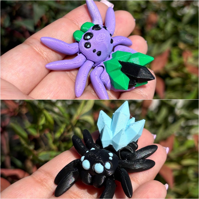 May include: Two 3D printed spider figurines. The first spider is purple with a green and black crystal on its back. The second spider is black with a light blue crystal on its back.