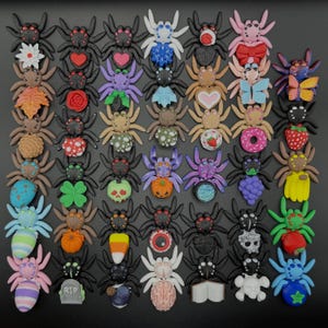 May include: A collection of small, colorful spider figurines arranged in a grid. Each spider features a unique design on its abdomen, including items like hearts, flowers, fruits, skulls, pumpkins, candy corn, brains, and various seasonal symbols.
