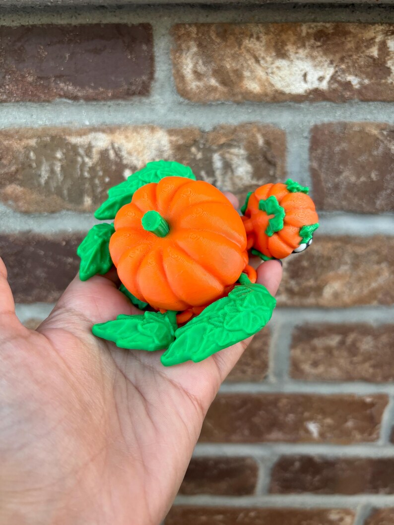 May include: A 3D printed pumpkin turtle figurine with green leaves and an orange pumpkin shell.