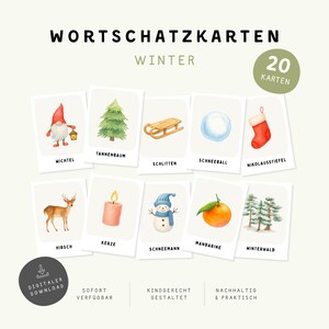 May include: A set of 20 winter-themed vocabulary cards featuring watercolour illustrations of a gnome, pine tree, sled, snowball, stocking, deer, candle, snowman, tangerine, and forest. The text includes 'WORTSCHATZ KARTEN WINTER' and '20 KARTEN'.