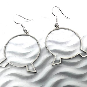 May include: A pair of silver hoop earrings with a unique design. The hoops are round with a small, pointed extension on each side.